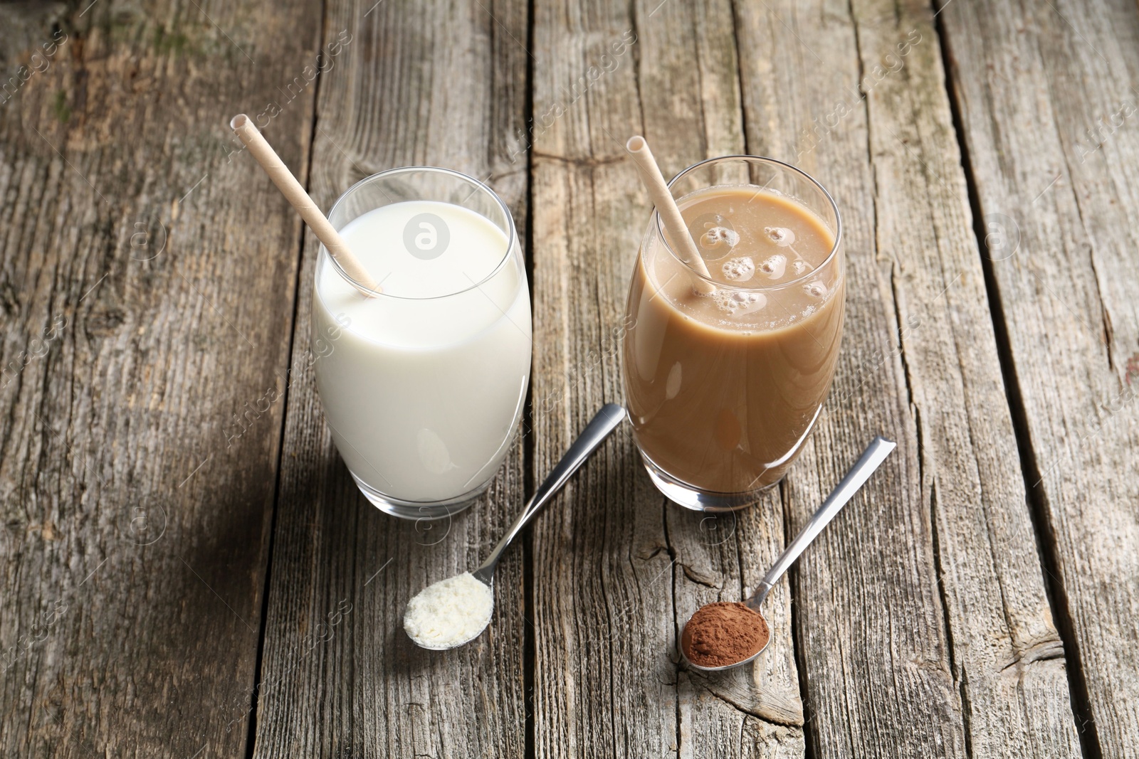 Photo of Delicious protein shakes in glasses and spoons with powder on wooden table