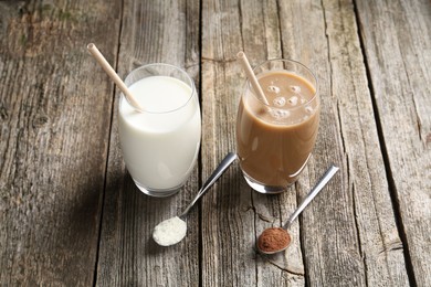 Photo of Delicious protein shakes in glasses and spoons with powder on wooden table