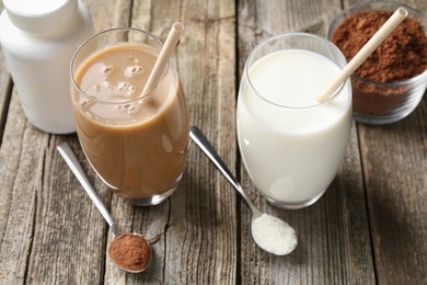 Photo of Delicious protein shakes in glasses and spoons with powder on wooden table