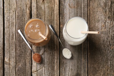 Photo of Delicious protein shakes in glasses and spoons with powder on wooden table, flat lay