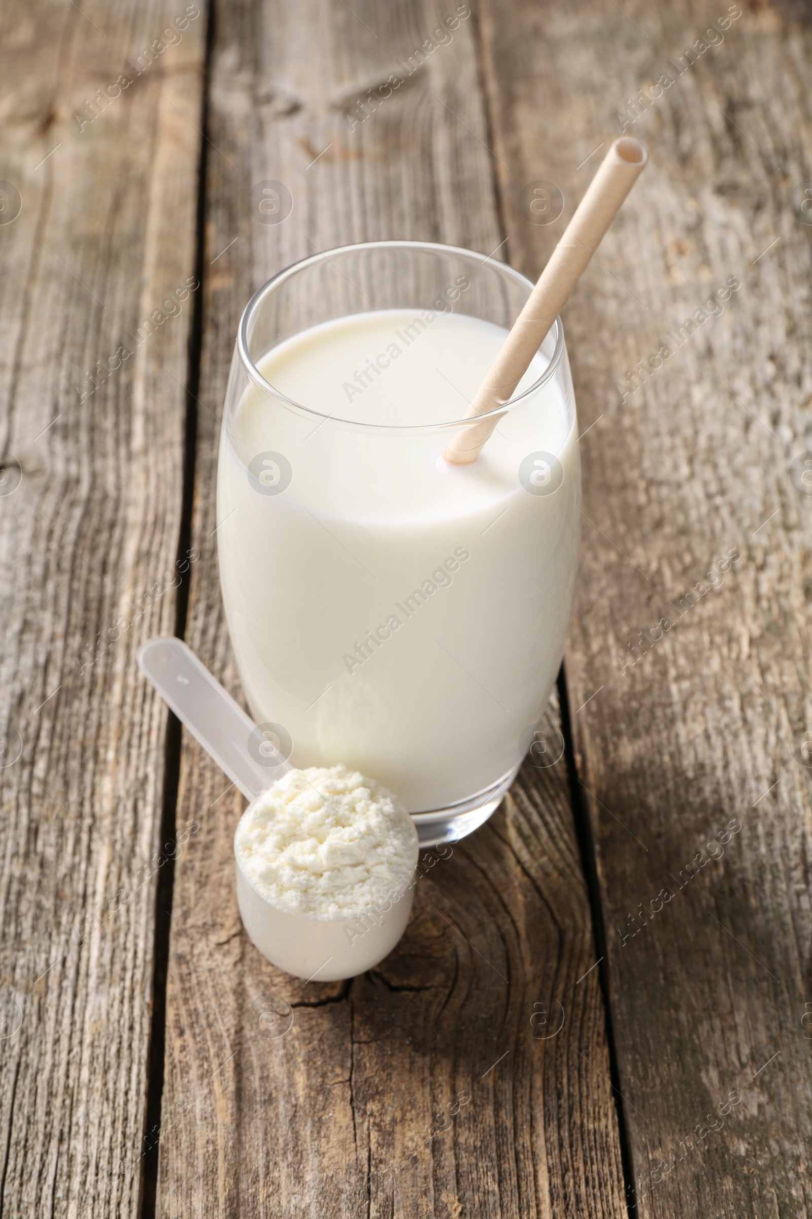 Photo of Delicious protein shake in glass and scoop with powder on wooden table