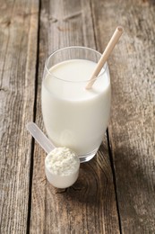 Photo of Delicious protein shake in glass and scoop with powder on wooden table