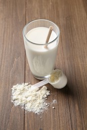 Photo of Delicious protein shake in glass, scoop and powder on wooden table