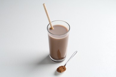 Photo of Delicious protein shake in glass and spoon with powder on white background