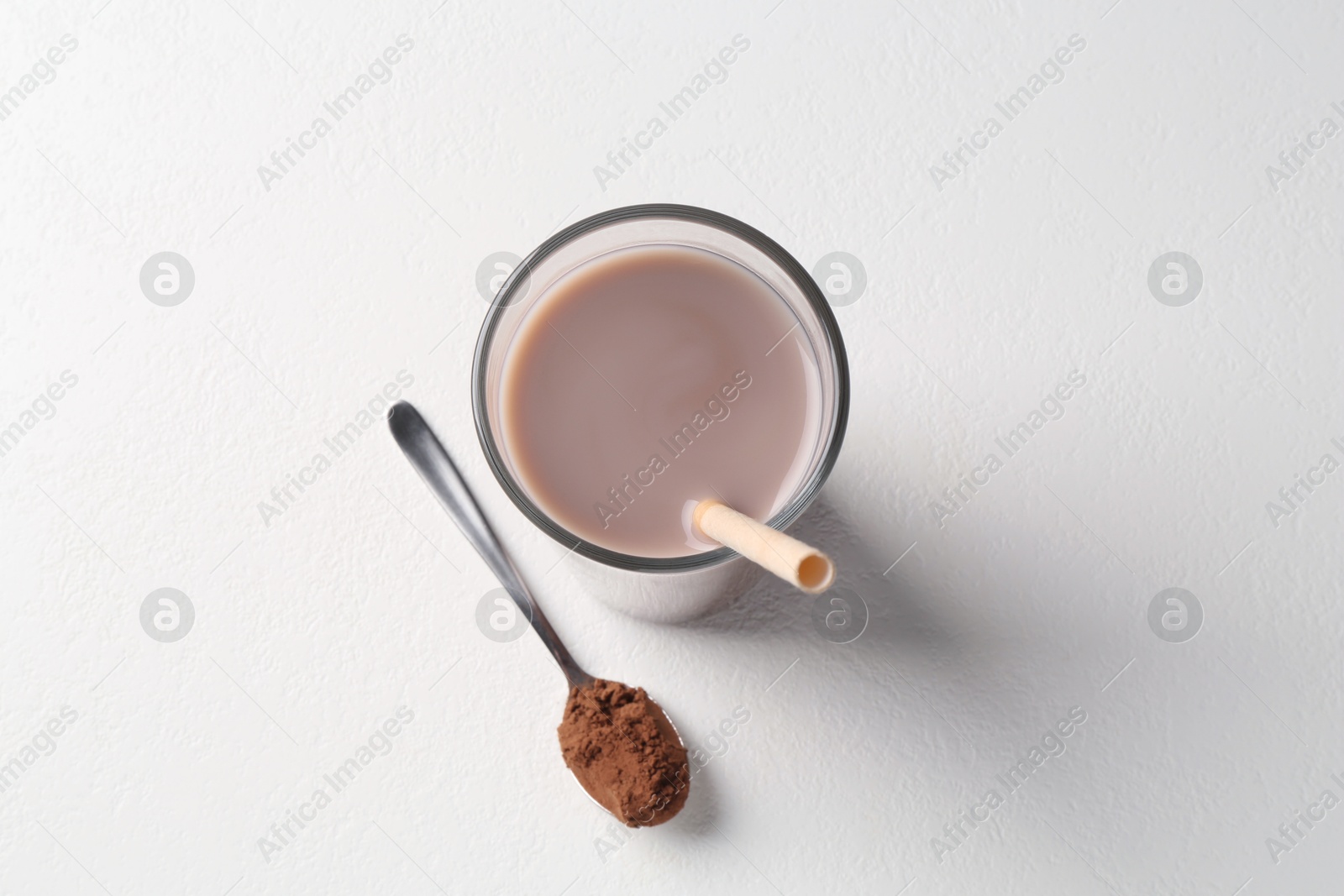 Photo of Delicious protein shake in glass and spoon with powder on white background, top view