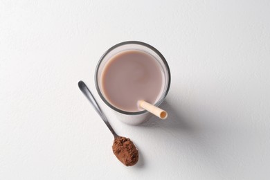 Photo of Delicious protein shake in glass and spoon with powder on white background, top view