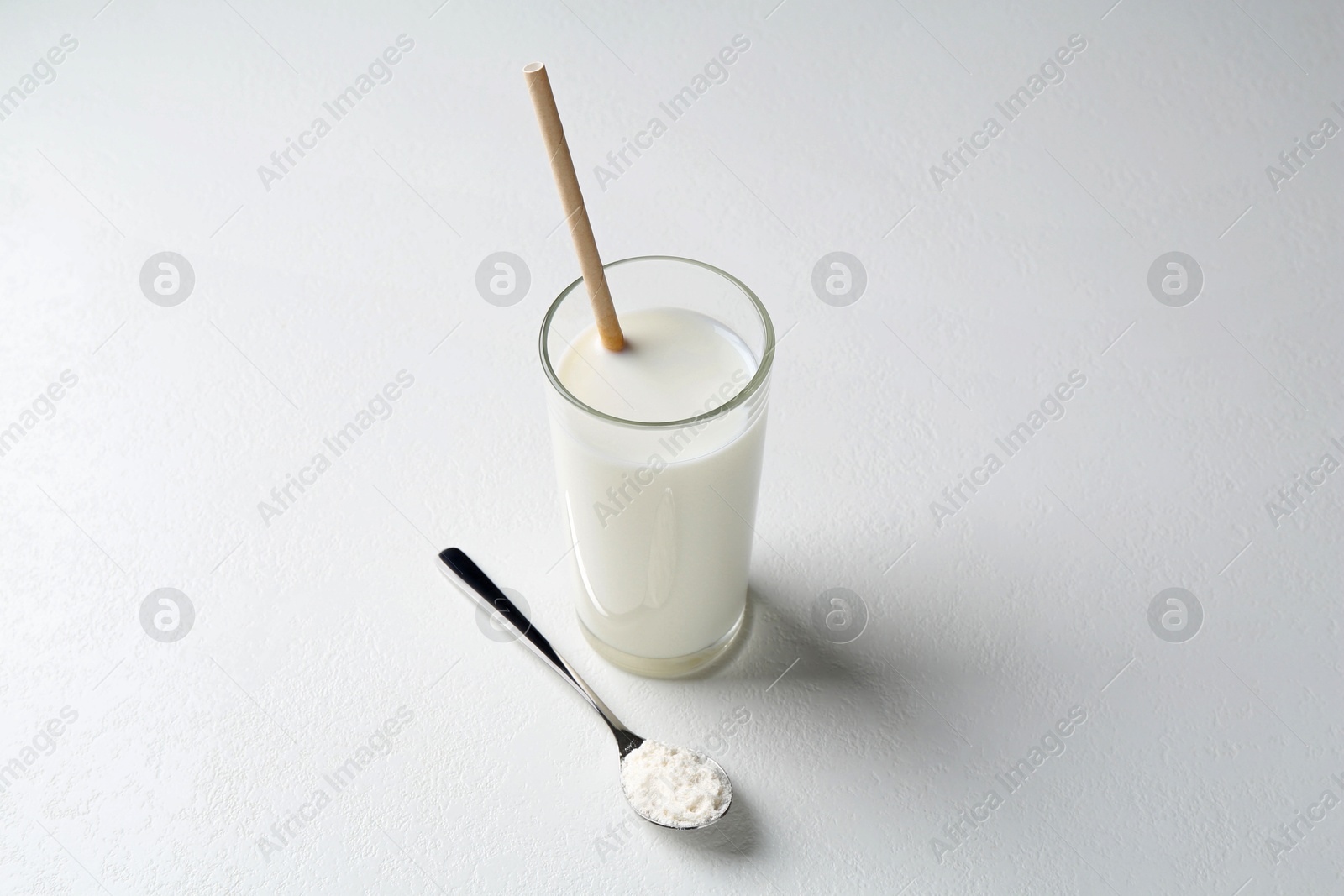 Photo of Delicious protein shake in glass and spoon with powder on white background