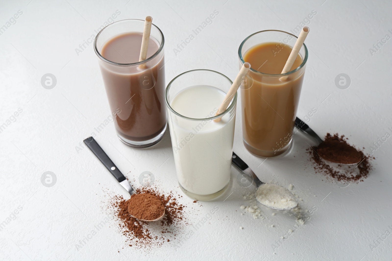 Photo of Delicious protein shakes in glasses and spoons with powder on white background