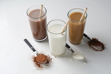 Photo of Delicious protein shakes in glasses and spoons with powder on white background