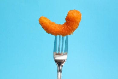 Photo of Fork with tasty fried shrimp on light blue background, closeup