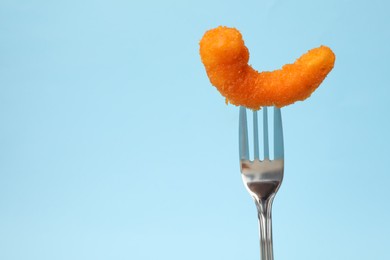 Photo of Fork with tasty fried shrimp on light blue background, closeup. Space for text