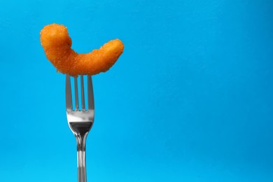 Photo of Fork with tasty fried shrimp on light blue background, closeup. Space for text