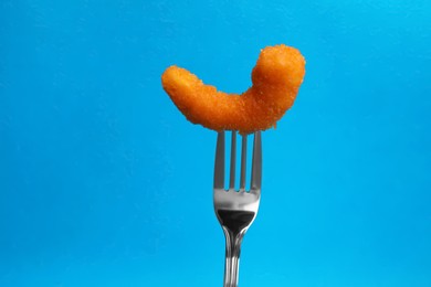 Fork with tasty fried shrimp on light blue background, closeup