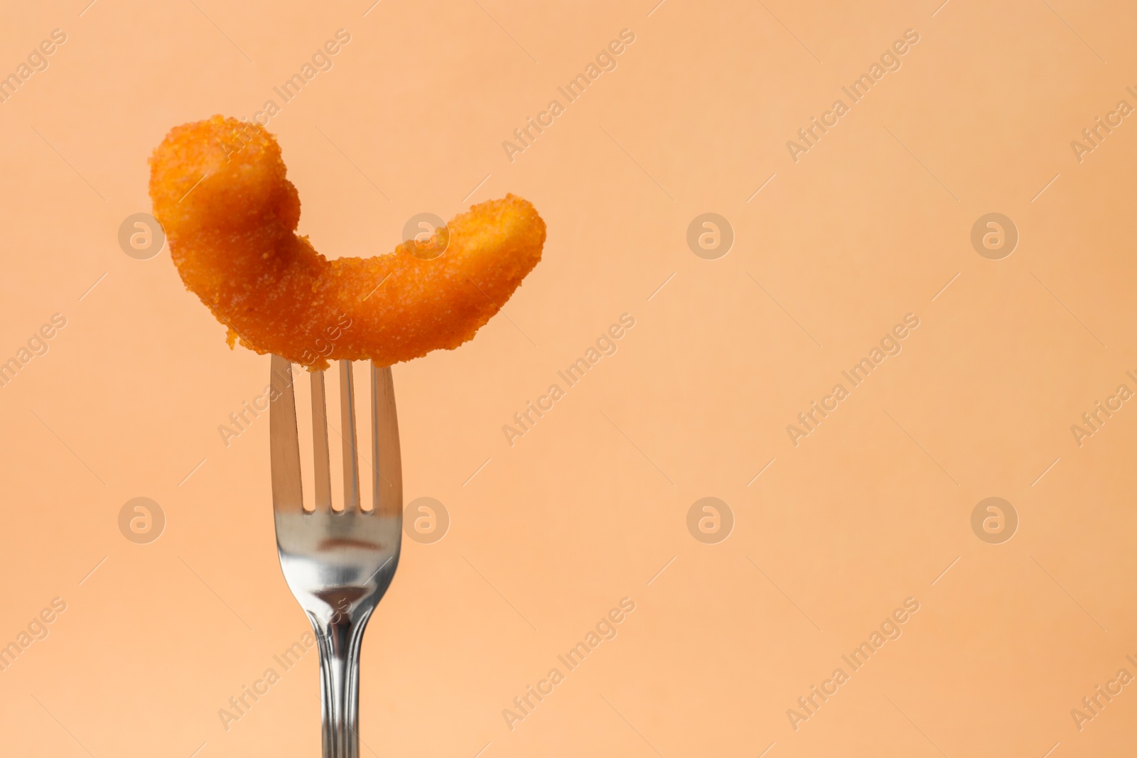 Photo of Fork with tasty fried shrimp on pale orange background, closeup. Space for text