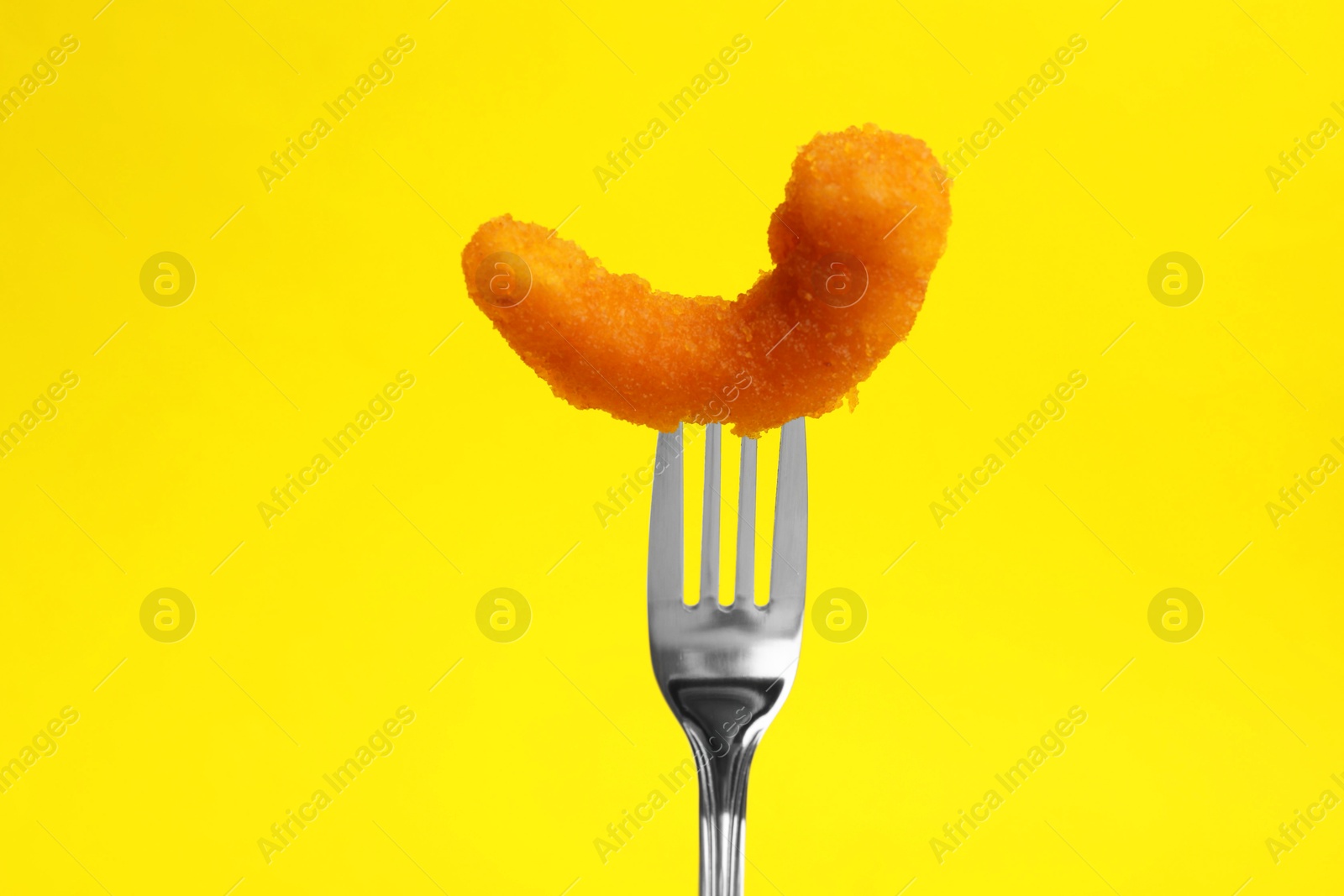 Photo of Fork with tasty fried shrimp on yellow background, closeup