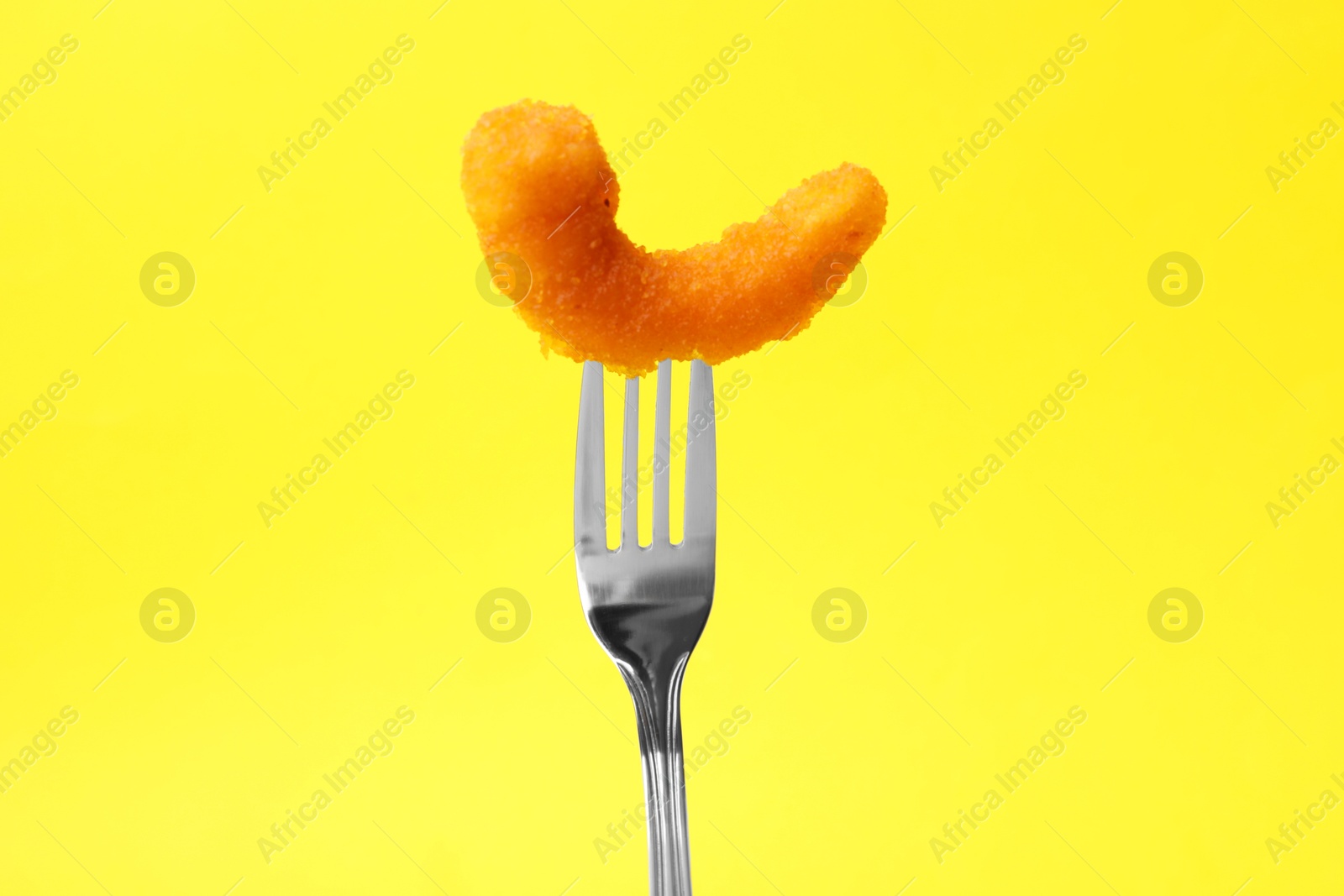 Photo of Fork with tasty fried shrimp on yellow background, closeup