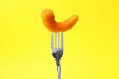 Fork with tasty fried shrimp on yellow background, closeup