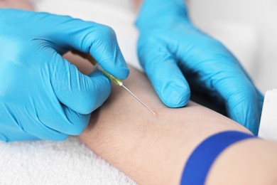 Photo of Nurse inserting IV into arm of patient in hospital, closeup