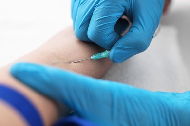 Nurse inserting IV into arm of patient in hospital, closeup