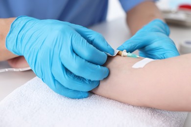 Nurse inserting IV into arm of patient in hospital, closeup