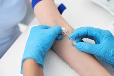 Photo of Nurse inputting catheter for IV drip in patient hand, closeup