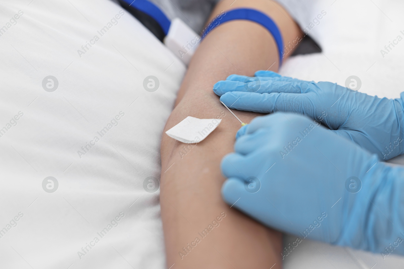 Photo of Nurse inserting IV into arm of patient in hospital, closeup