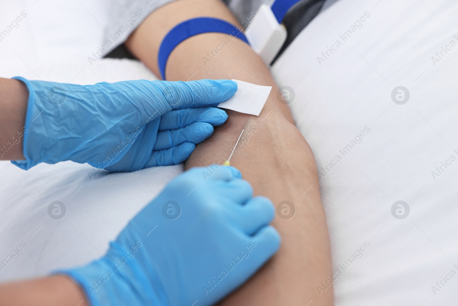 Photo of Nurse inserting IV into arm of patient in hospital, closeup