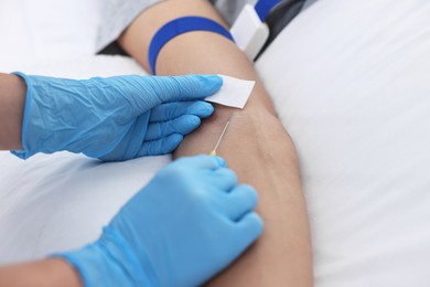 Nurse inserting IV into arm of patient in hospital, closeup