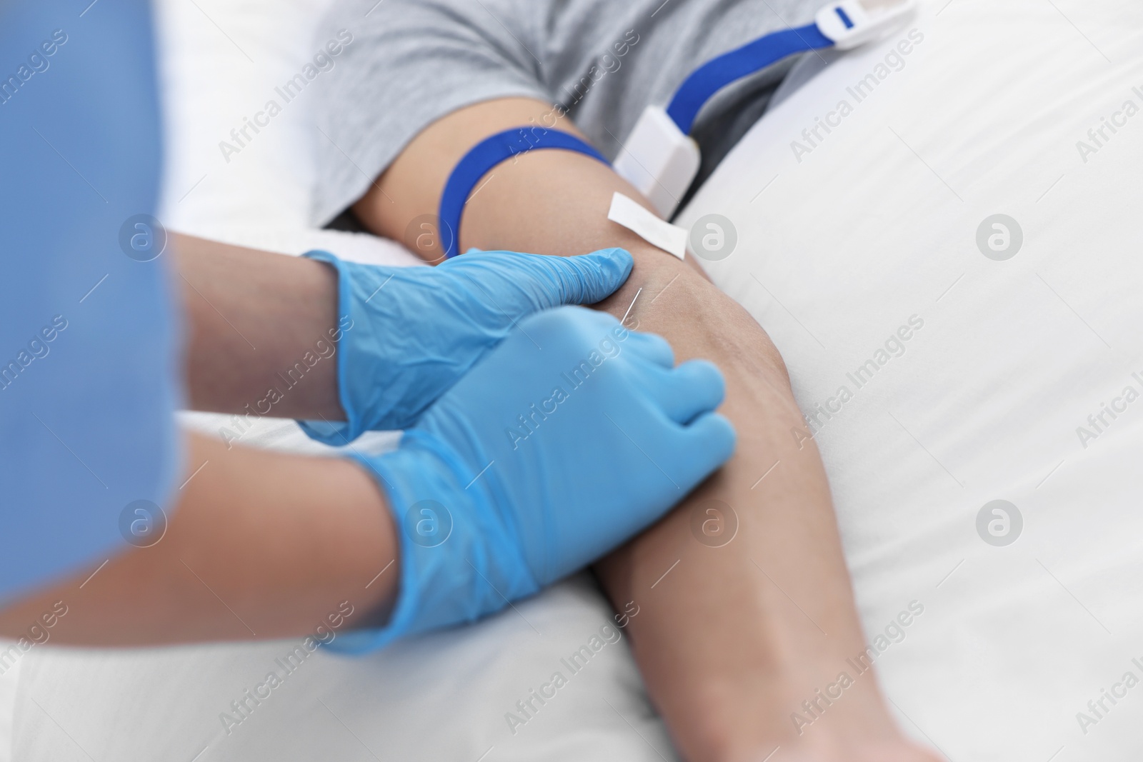 Photo of Nurse inserting IV into arm of patient in hospital, closeup