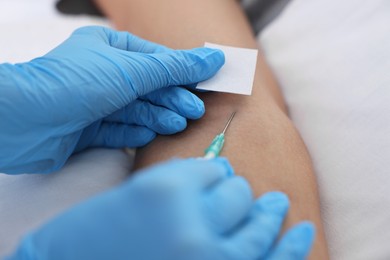 Nurse inserting IV into arm of patient in hospital, closeup