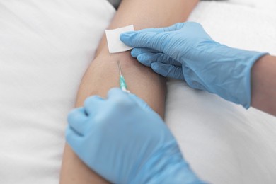 Nurse inserting IV into arm of patient in hospital, closeup