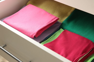 Photo of Chest of drawers with different folded clothes, closeup