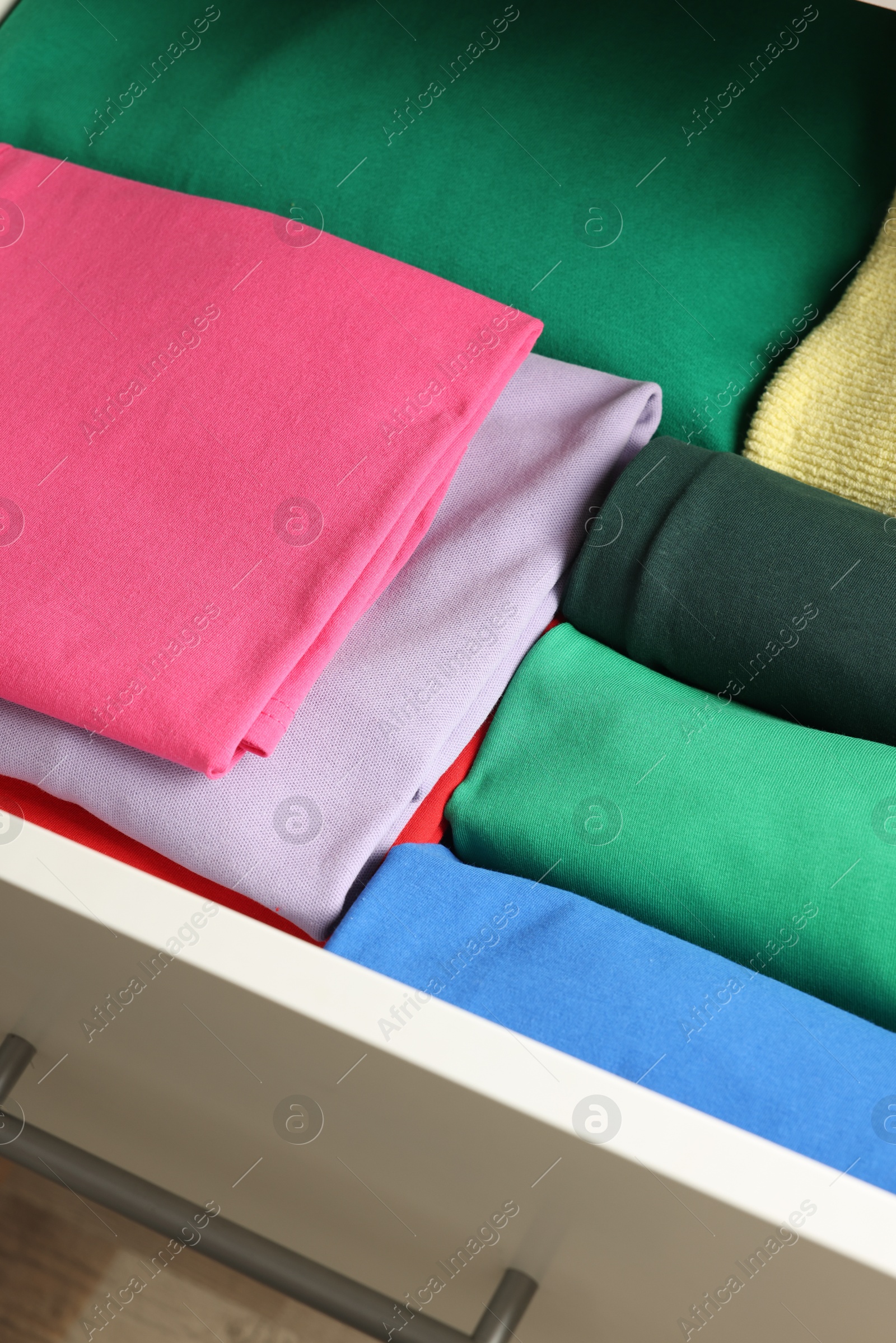 Photo of Chest of drawers with different folded clothes, closeup