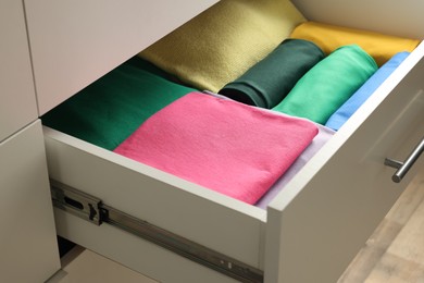 Chest of drawers with different folded clothes, closeup