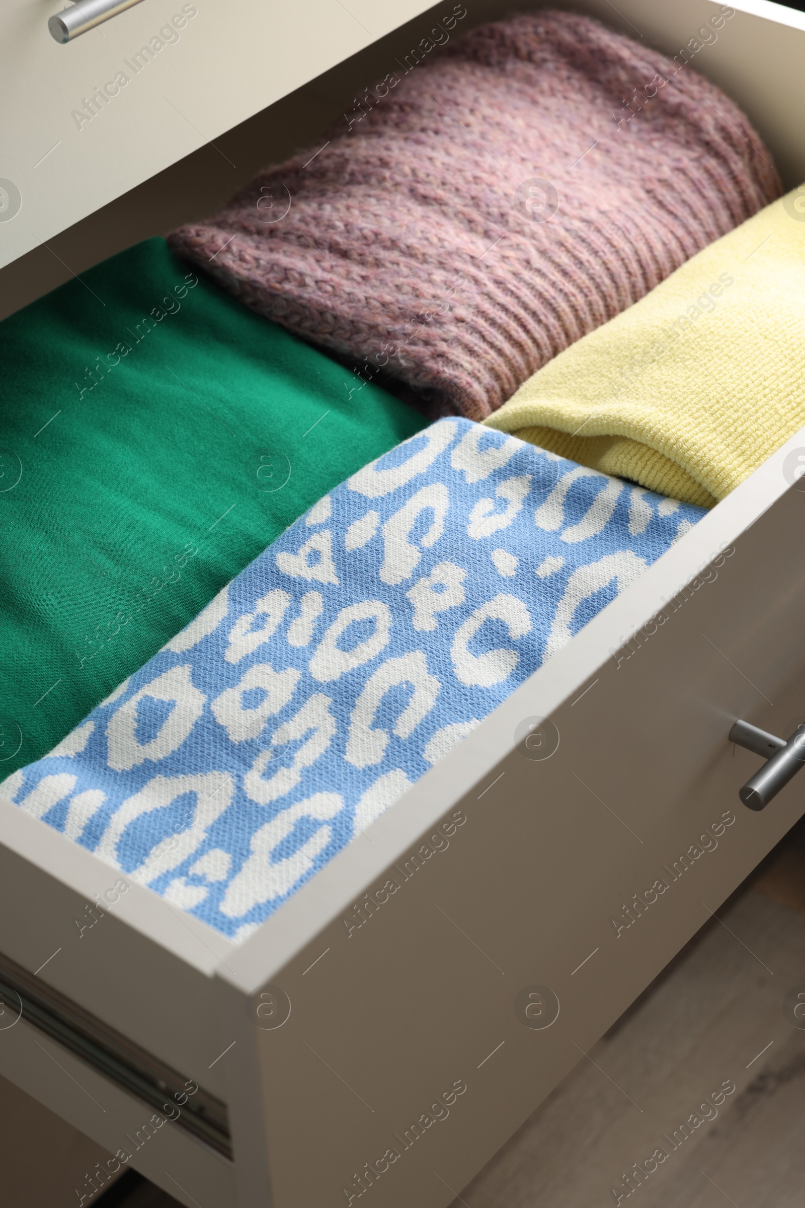 Photo of Chest of drawers with different folded clothes, closeup