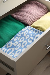 Chest of drawers with different folded clothes, closeup