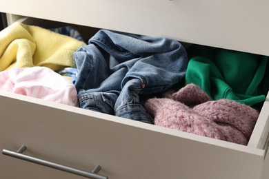 Photo of Cluttered chest of drawers indoors, closeup. Clothes in mess