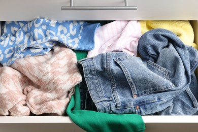 Cluttered chest of drawers indoors, closeup. Clothes in mess