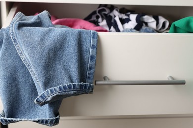 Photo of Cluttered chest of drawers indoors, closeup. Clothes in mess