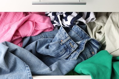 Cluttered chest of drawers indoors, above view. Clothes in mess