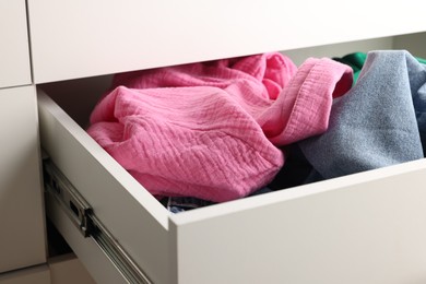 Cluttered chest of drawers indoors, closeup. Clothes in mess