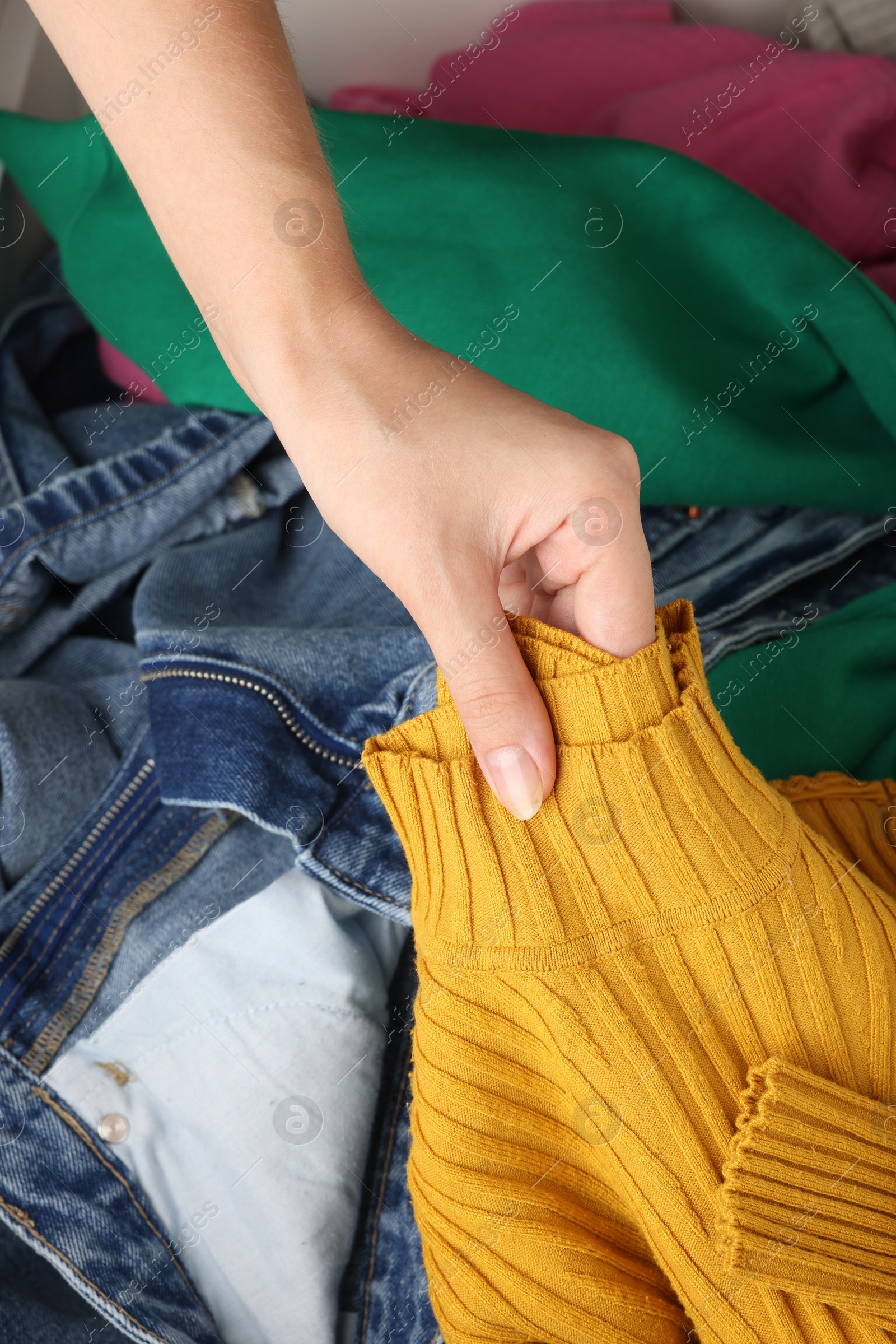 Photo of Woman organizing clothes in chest of drawers indoors, closeup