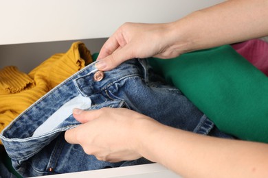 Photo of Woman organizing clothes in chest of drawers indoors, closeup