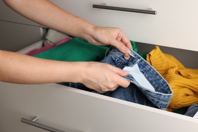 Photo of Woman organizing clothes in chest of drawers indoors, closeup