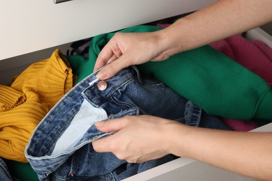 Woman organizing clothes in chest of drawers indoors, closeup