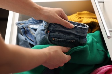 Woman organizing clothes in chest of drawers indoors, closeup