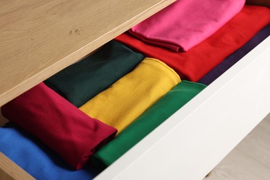 Photo of Chest of drawers with different folded clothes, closeup