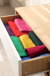 Photo of Chest of drawers with different folded clothes, closeup