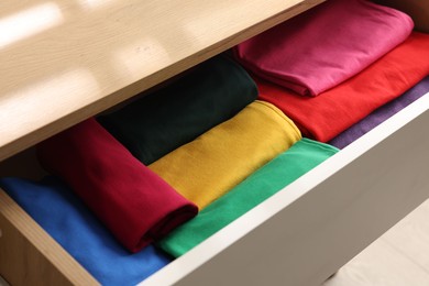 Photo of Chest of drawers with different folded clothes, closeup