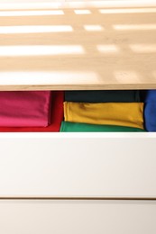 Photo of Chest of drawers with different folded clothes, closeup